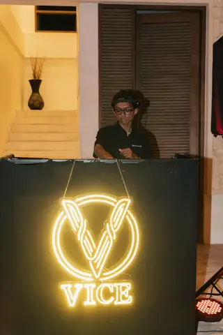 The DJ behind the booth, the VICE neon sign hung on the front