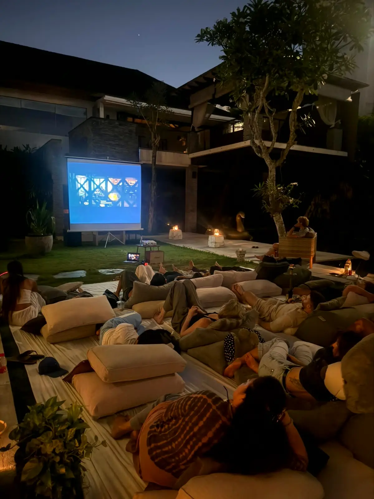 Guests lying on floor cushions watching the screen in the garden