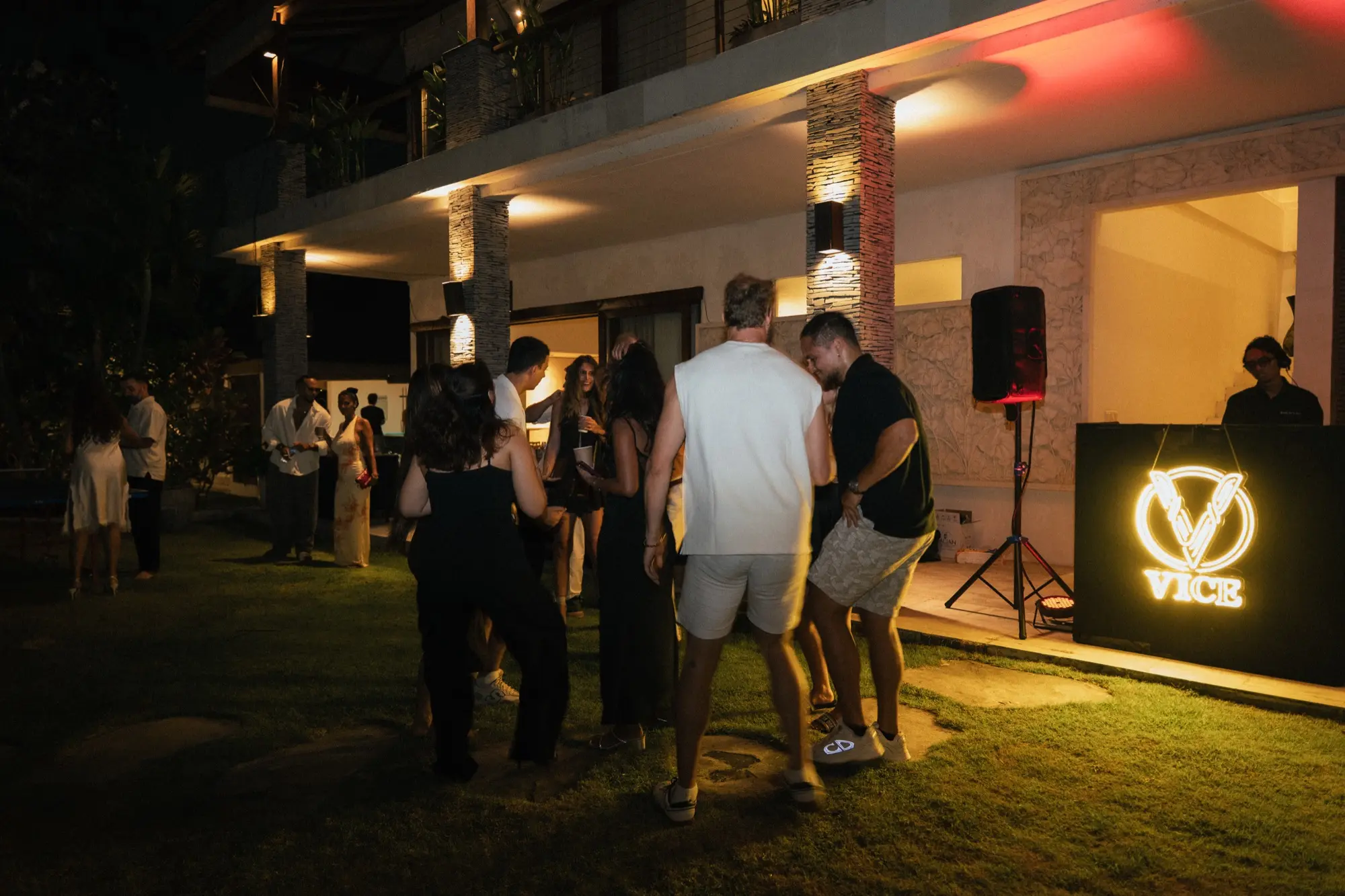 Guests dancing on the lawn at Edition 01, the VICE neon sign glowing by the DJ
