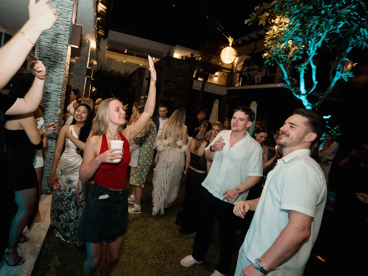 Guests dancing in the garden, arms up, the villa lit behind them